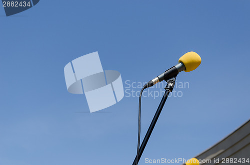 Image of yellow microphone on blue sky background 
