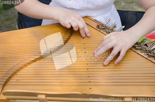 Image of ancient stringed baltic psaltery and girls hands 