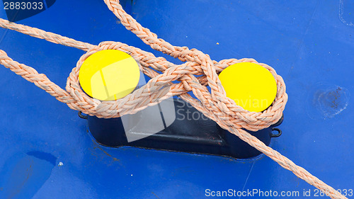 Image of Twisted orange rope round a yellow bollard