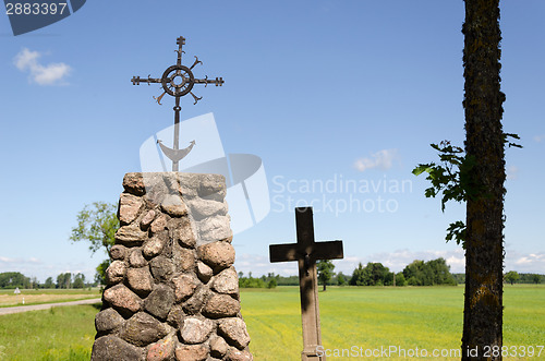 Image of stone monument with metal squirm cross in nature  