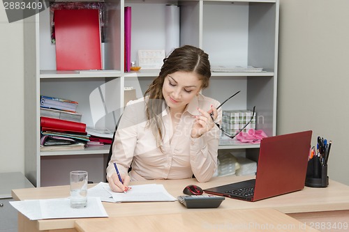 Image of Girl writes on a piece of paper in the office