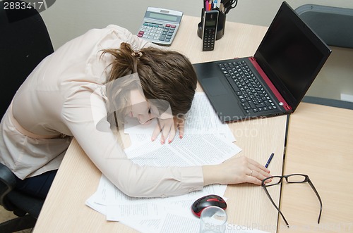 Image of Tired woman asleep on a workplace at office