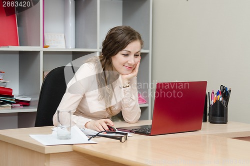 Image of Smiling girl views a page on social networks in office