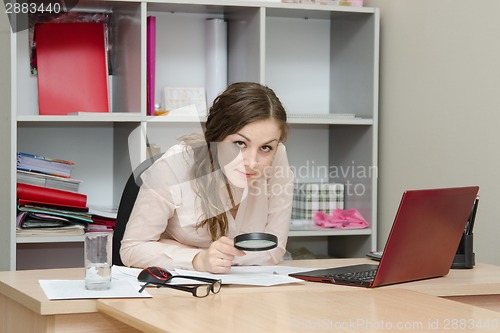 Image of Girl considers the document into a magnifying glass