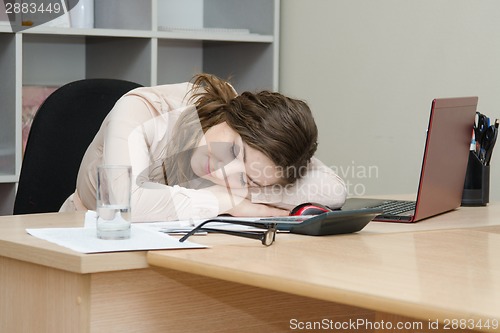 Image of The girl fell asleep at his laptop in the office