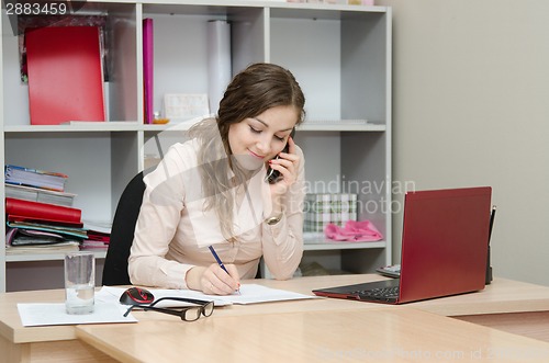 Image of Business woman calling by phone and does records