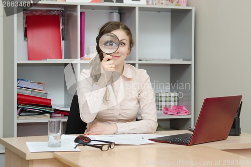 Image of Girl looking through a magnifying glass in the office