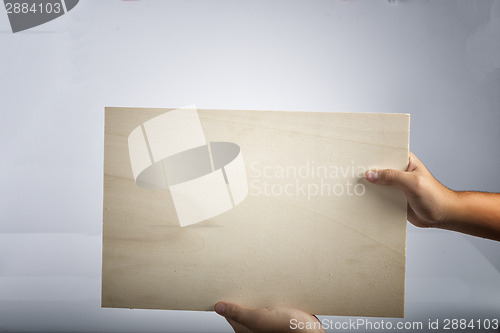 Image of Plywood sign held up by young hands