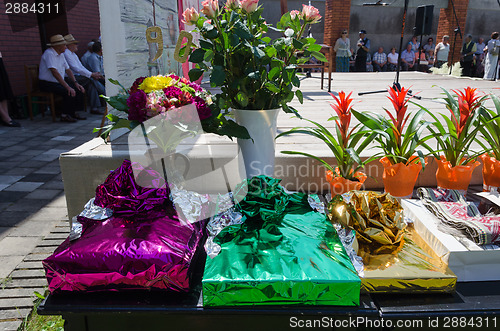 Image of gift in glossy paper and bouquets on table outdoor 