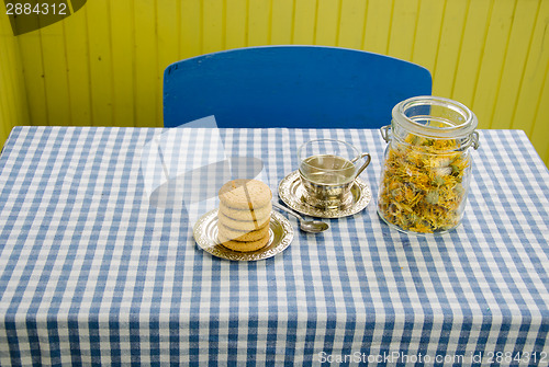 Image of dried marigold dish with cup and cookies on table 