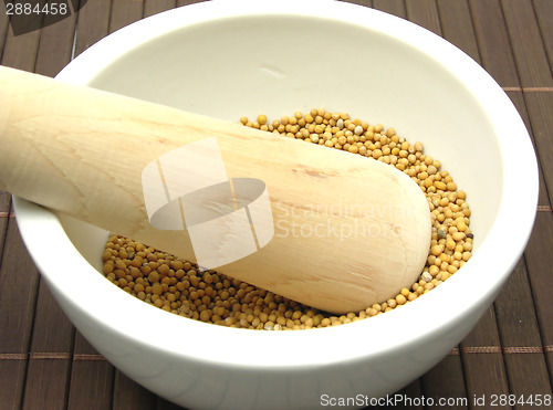 Image of Pestling grains of mustard seed  in a bowl of chinaware