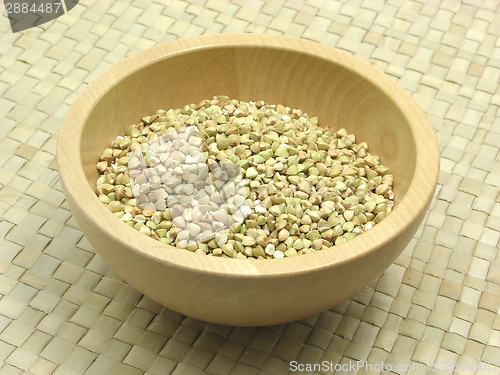 Image of Wooden bowl with buckwheat on rattan underlay