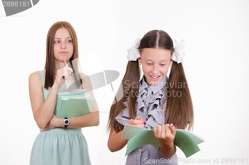 Image of The teacher looks at the student with a notebook