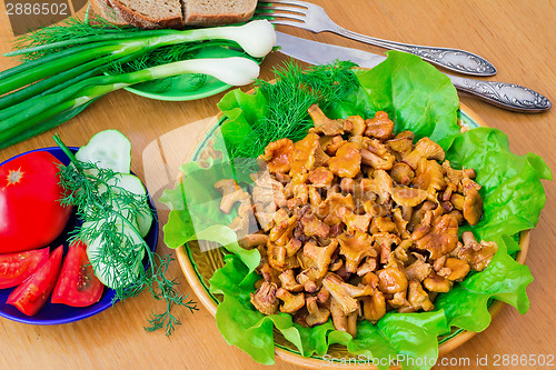 Image of Fried mushrooms of chanterelle on a dish together with lettuce l