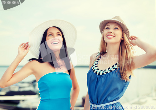 Image of girls in dresses with hats on the beach