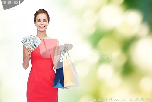 Image of smiling elegant woman in dress with shopping bags