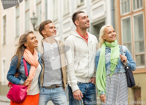 Image of group of smiling friends walking in the city