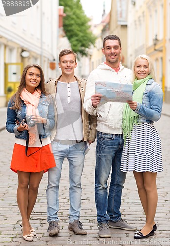 Image of group of smiling friends with map and photocamera