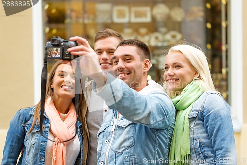 Image of group of smiling friends making selfie outdoors