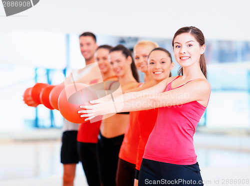 Image of group of smiling people working out with ball