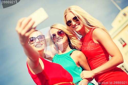 Image of smiling girls taking photo with smartphone camera