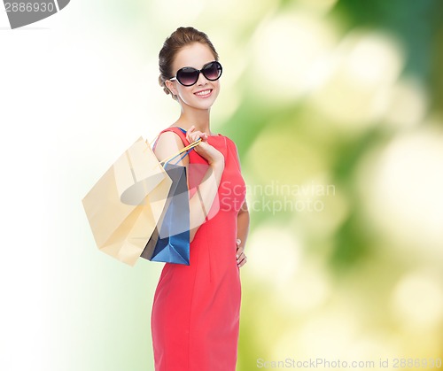 Image of smiling elegant woman in dress with shopping bags