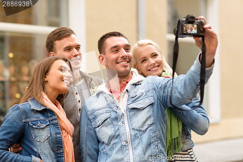 Image of group of smiling friends making selfie outdoors