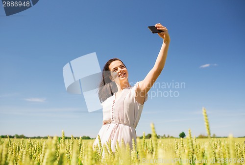 Image of smiling girl with smartphone on cereal field