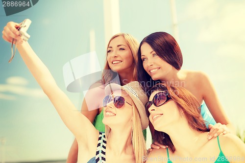 Image of smiling girls taking photo in cafe on the beach