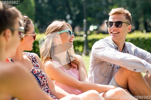 Image of group of smiling friends outdoors sitting in park