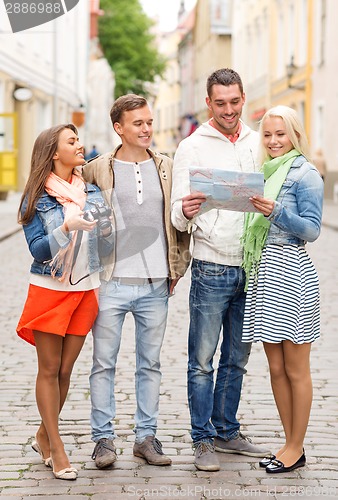 Image of group of smiling friends with map and photocamera