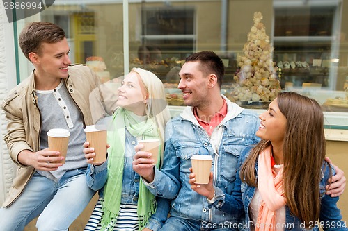 Image of group of smiling friends with take away coffee