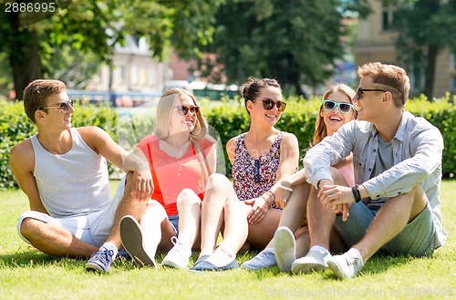Image of group of smiling friends outdoors sitting on grass