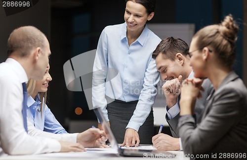 Image of smiling female boss talking to business team