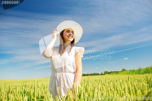 Image of smiling young woman in straw hat on cereal field