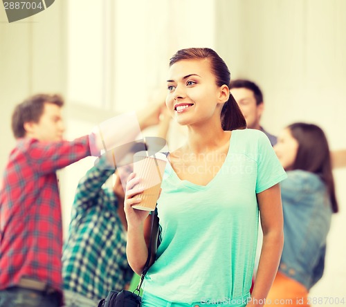 Image of student holding take away coffee cup in college