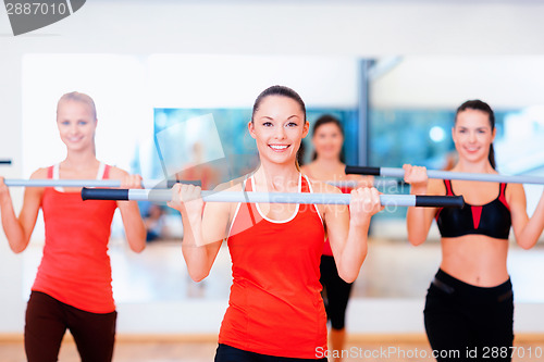 Image of group of smiling people working out with barbells