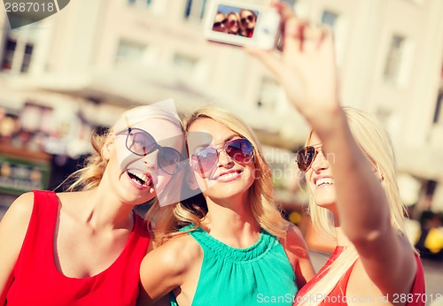 Image of girls taking picture with camera in the city