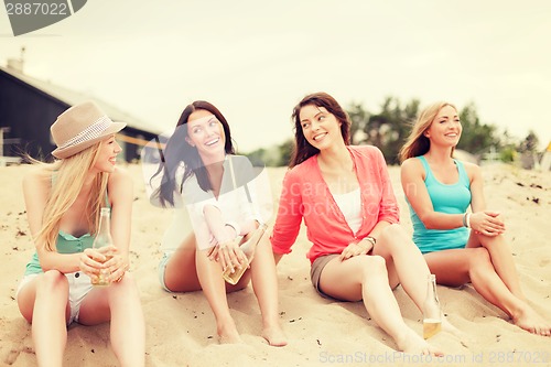 Image of smiling girls with drinks on the beach