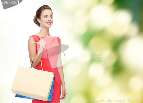 Image of smiling elegant woman in dress with shopping bags