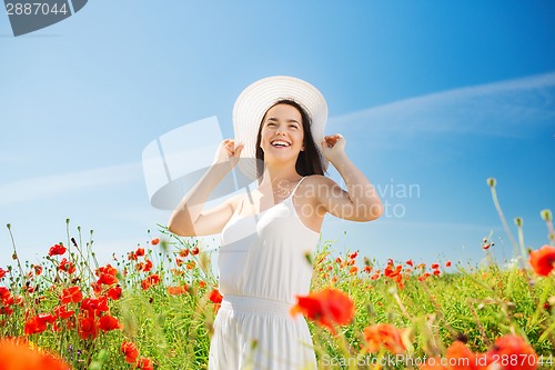 Image of smiling young woman in straw hat on poppy field