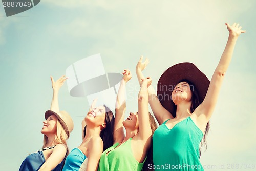 Image of smiling girls with hands up on the beach