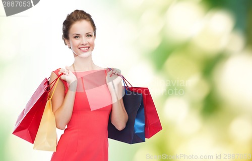Image of smiling elegant woman in dress with shopping bags