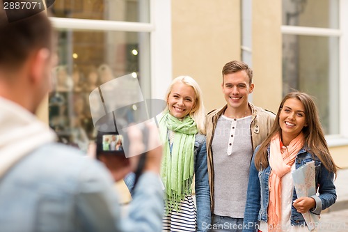 Image of group of smiling friends taking photo outdoors