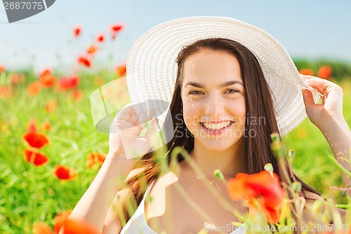 Image of smiling young woman in straw hat on poppy field