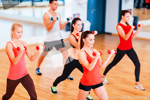 Image of group of smiling people working out with dumbbells