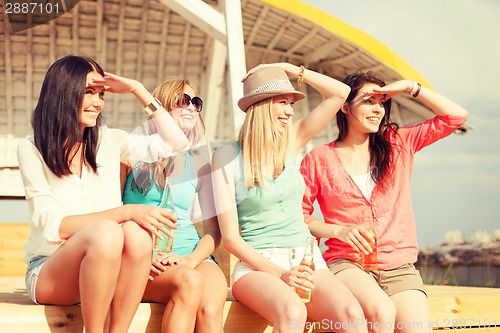 Image of smiling girls with drinks on the beach