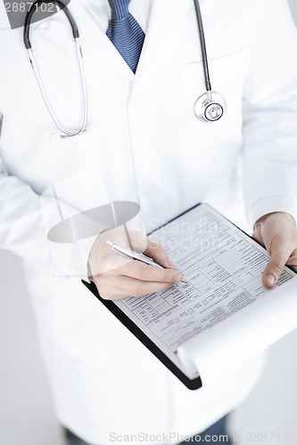 Image of male doctor holding prescription paper in hand