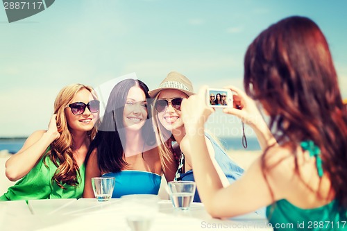 Image of girls taking photo in cafe on the beach