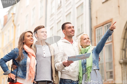 Image of group of smiling friends with map and photocamera